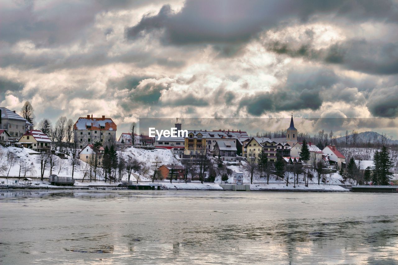 BUILDINGS BY RIVER AGAINST SKY