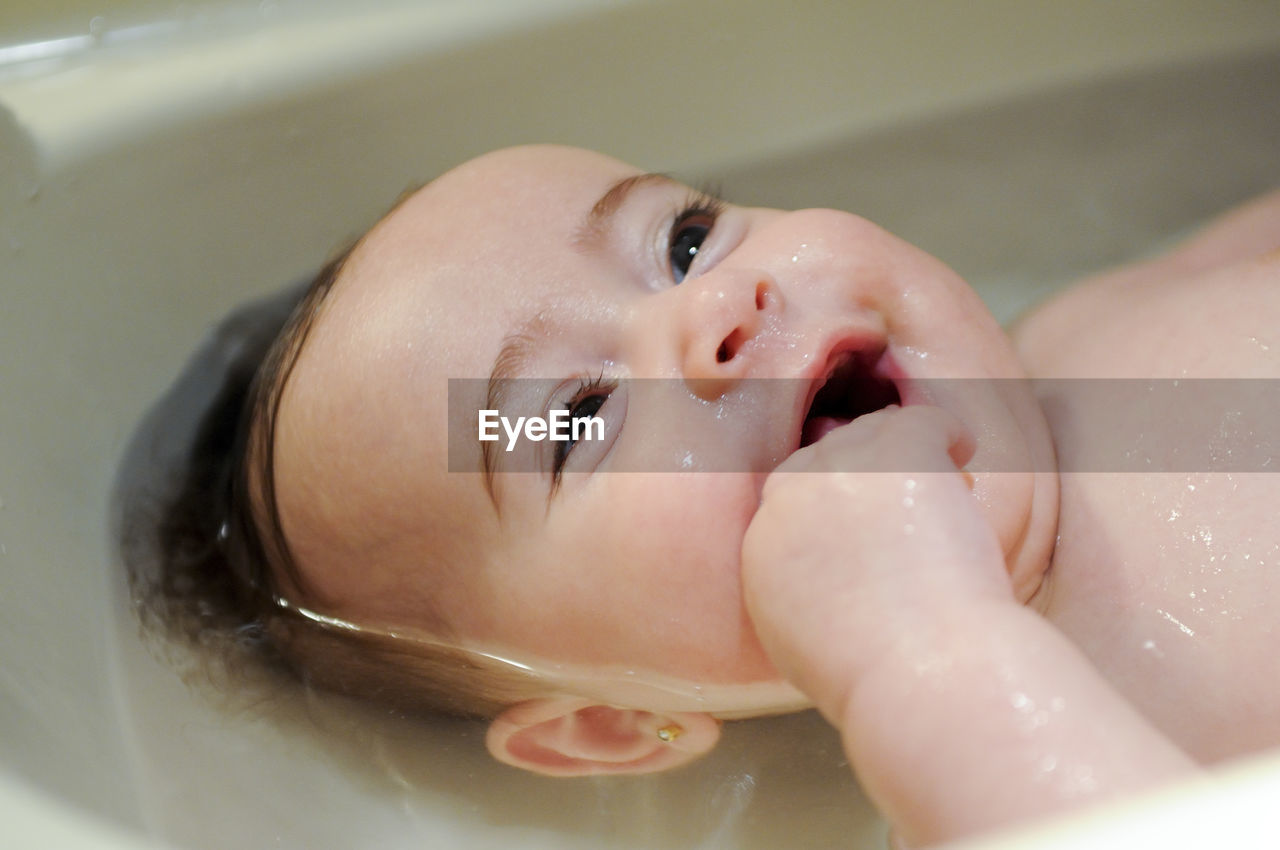 Close-up of cute baby boy in bathtub at bathroom