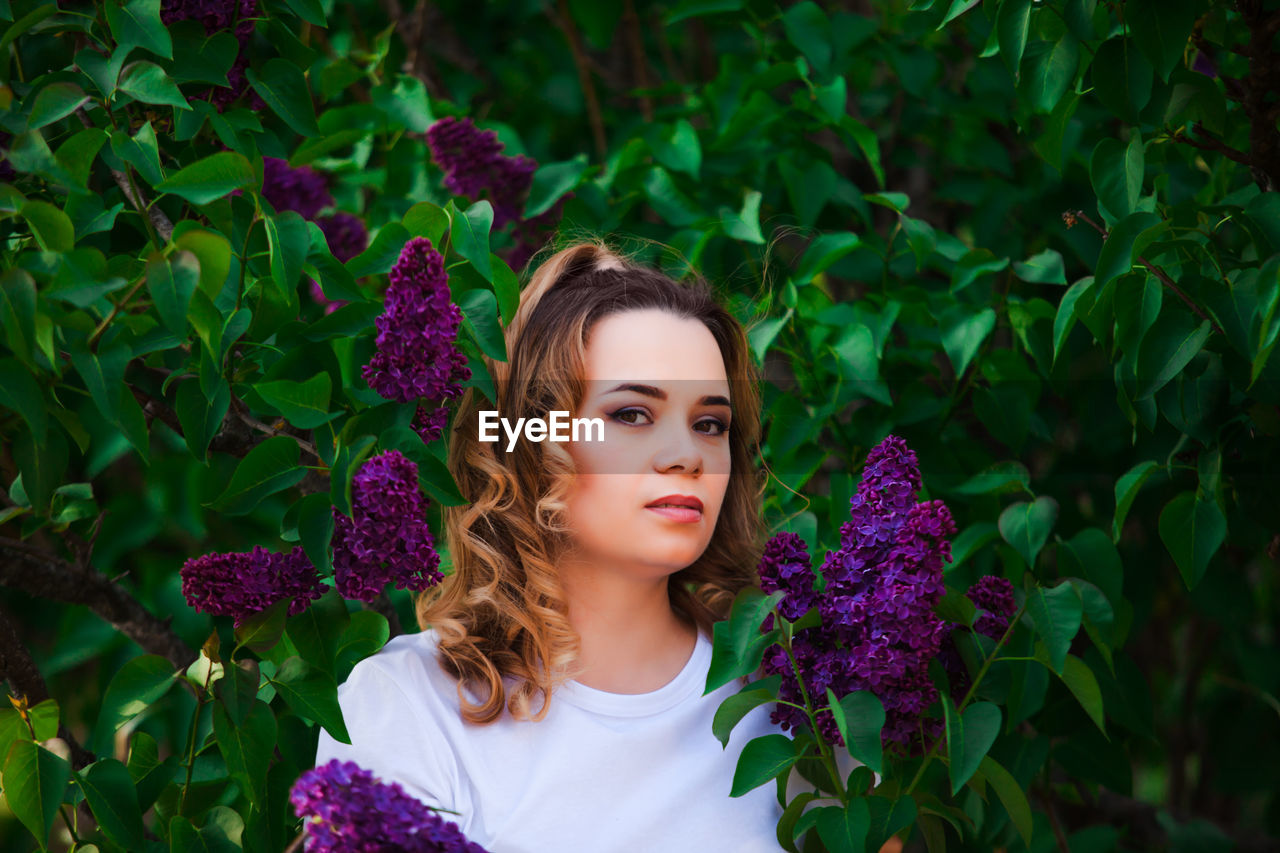 PORTRAIT OF BEAUTIFUL YOUNG WOMAN WITH PURPLE FLOWERS