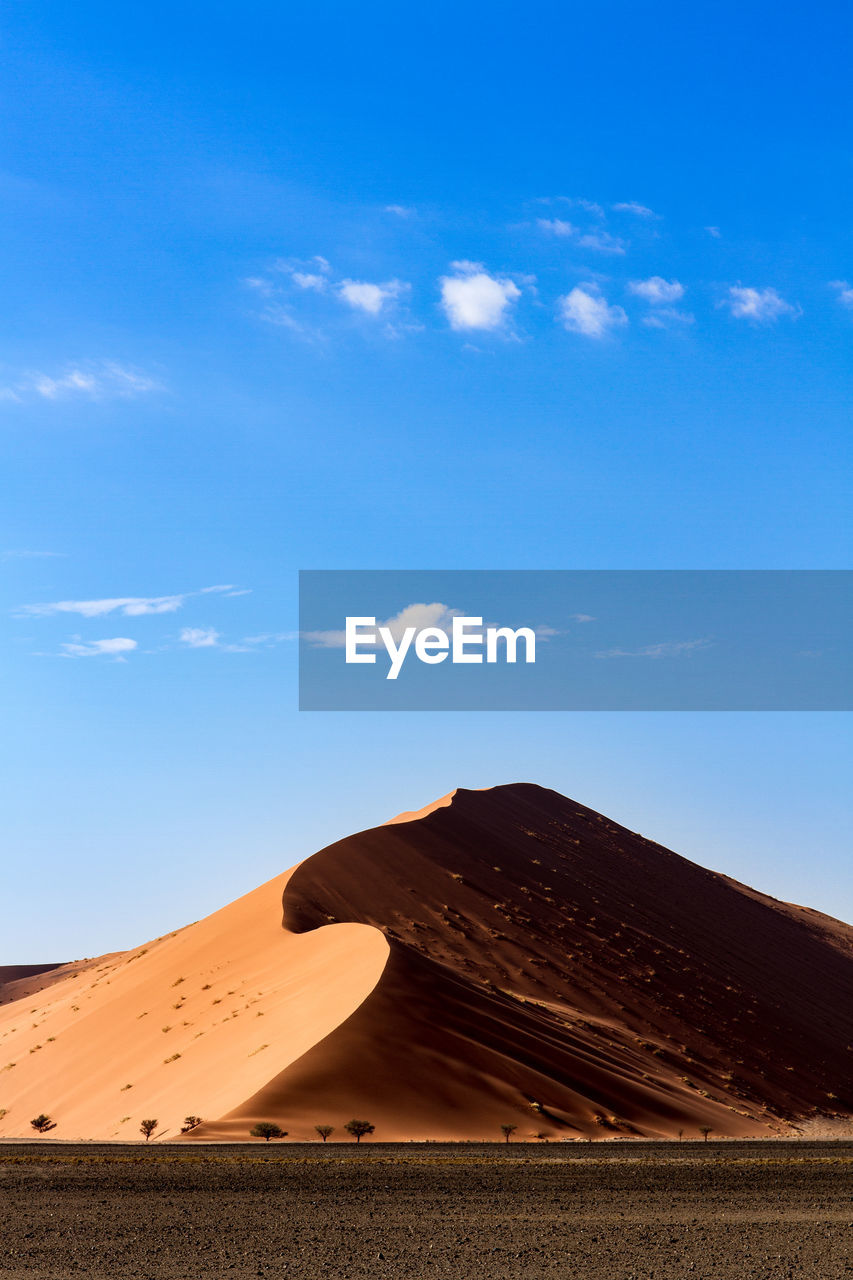 Landscape and sand dune against blue sky