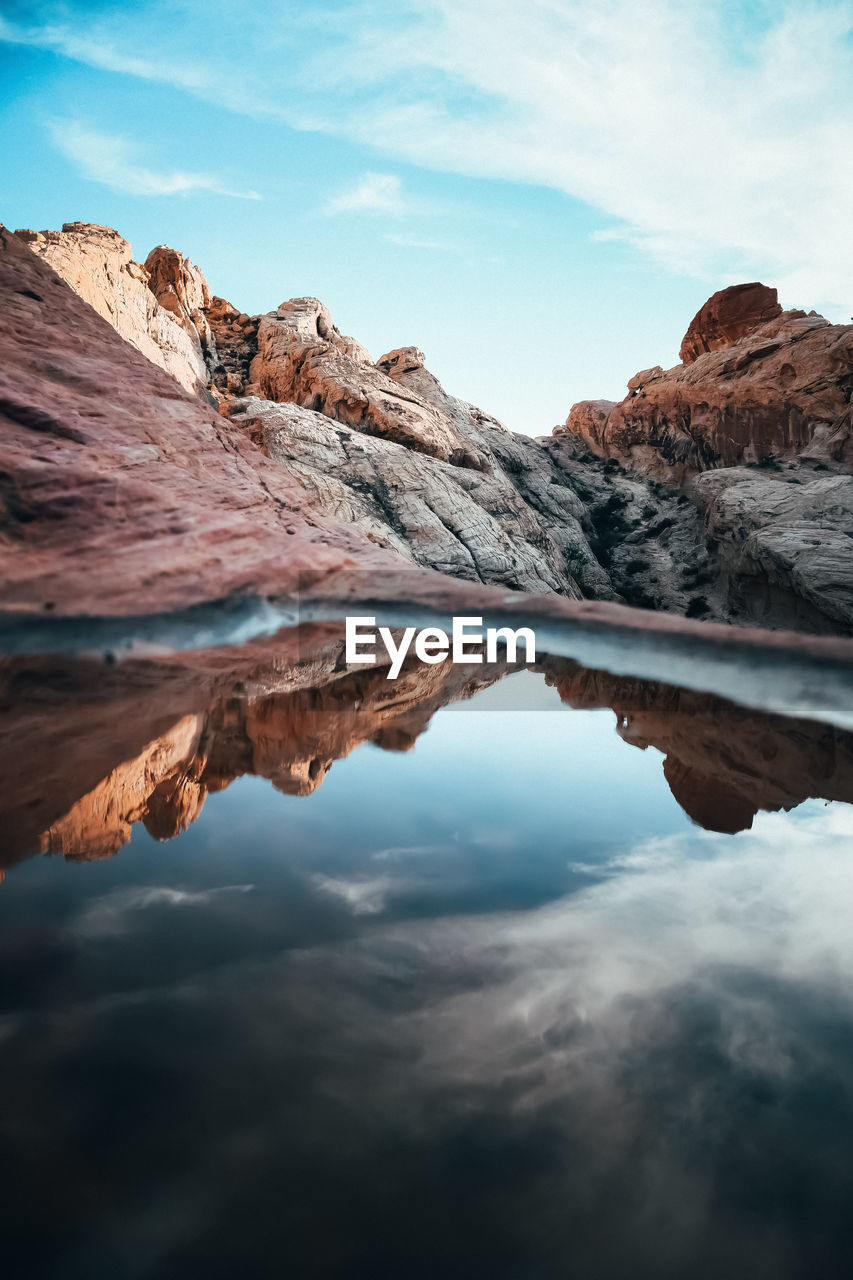 Scenic view of mountains reflecting in water against sky