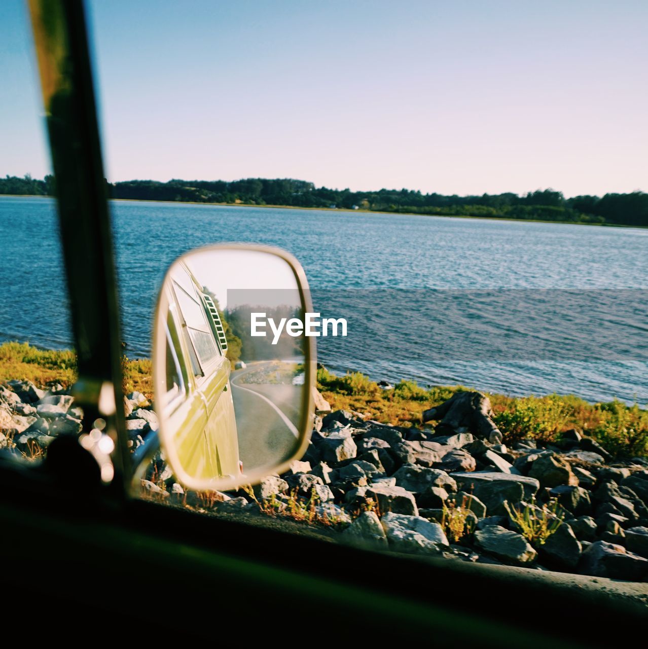 Reflection of van on side-view mirror against sea