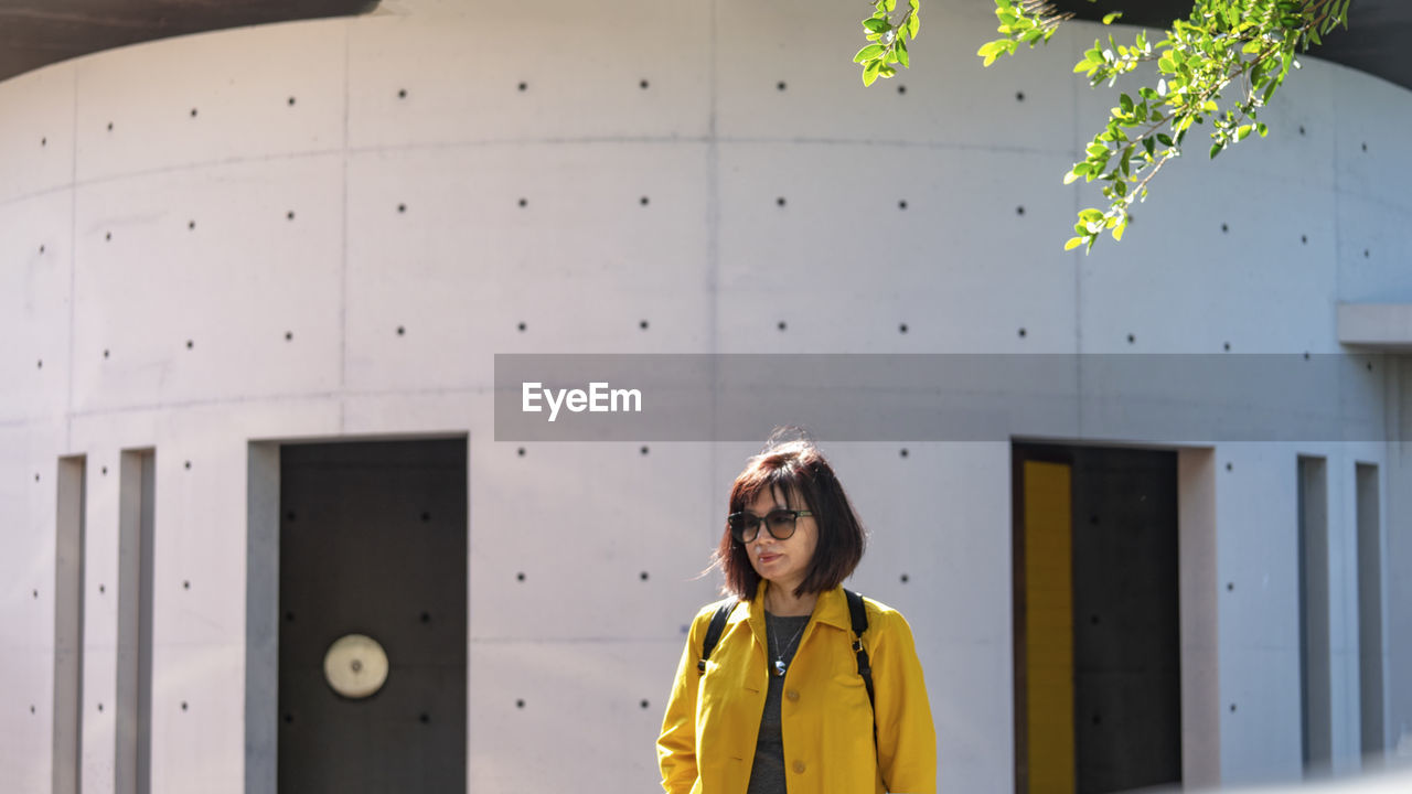 Portrait of woman standing against yellow wall