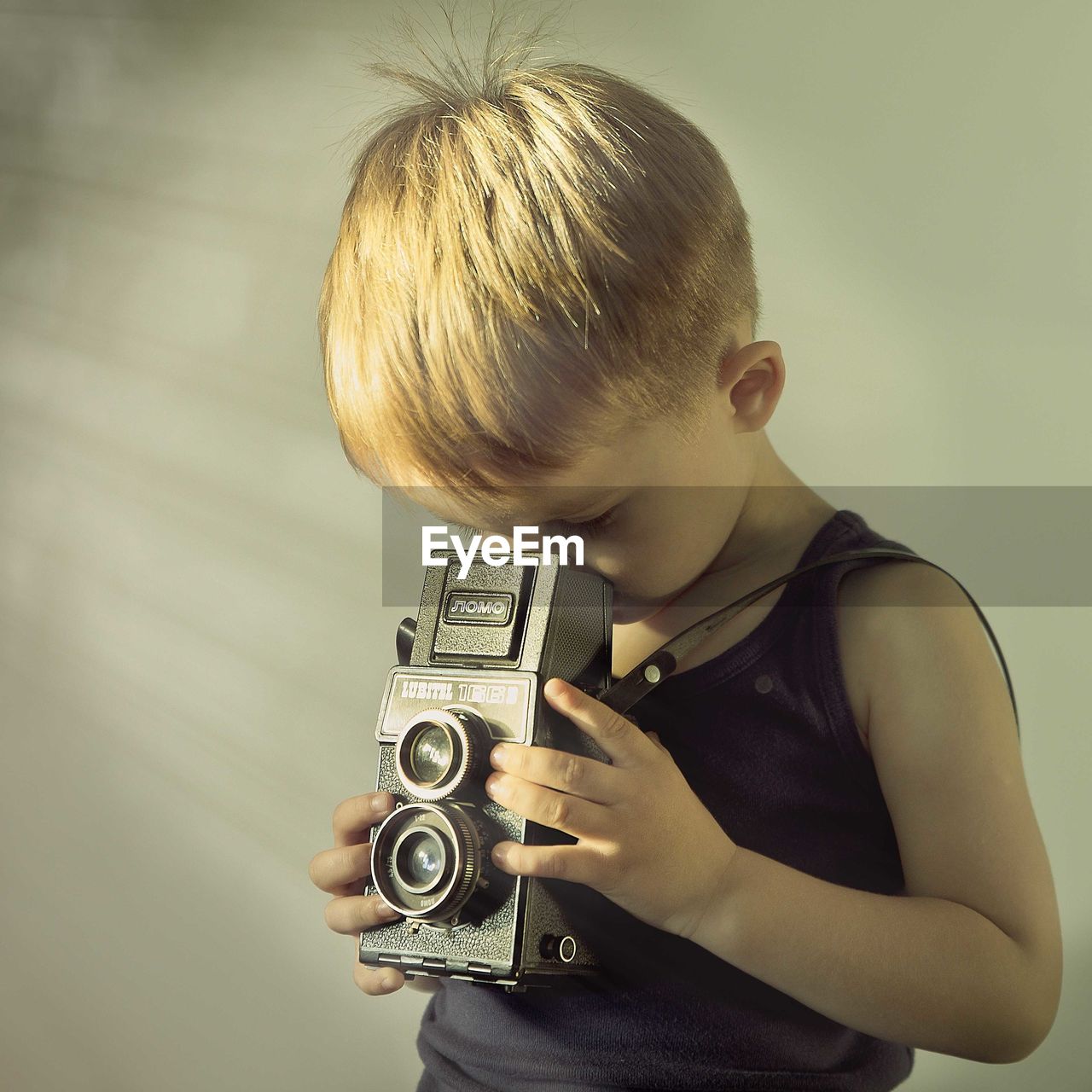 Boy photographing by analog camera at home