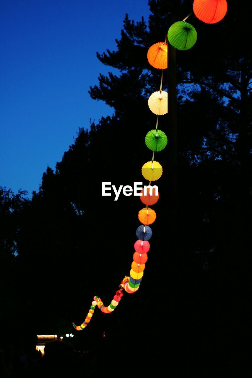 LOW ANGLE VIEW OF ILLUMINATED LANTERNS HANGING AGAINST SKY