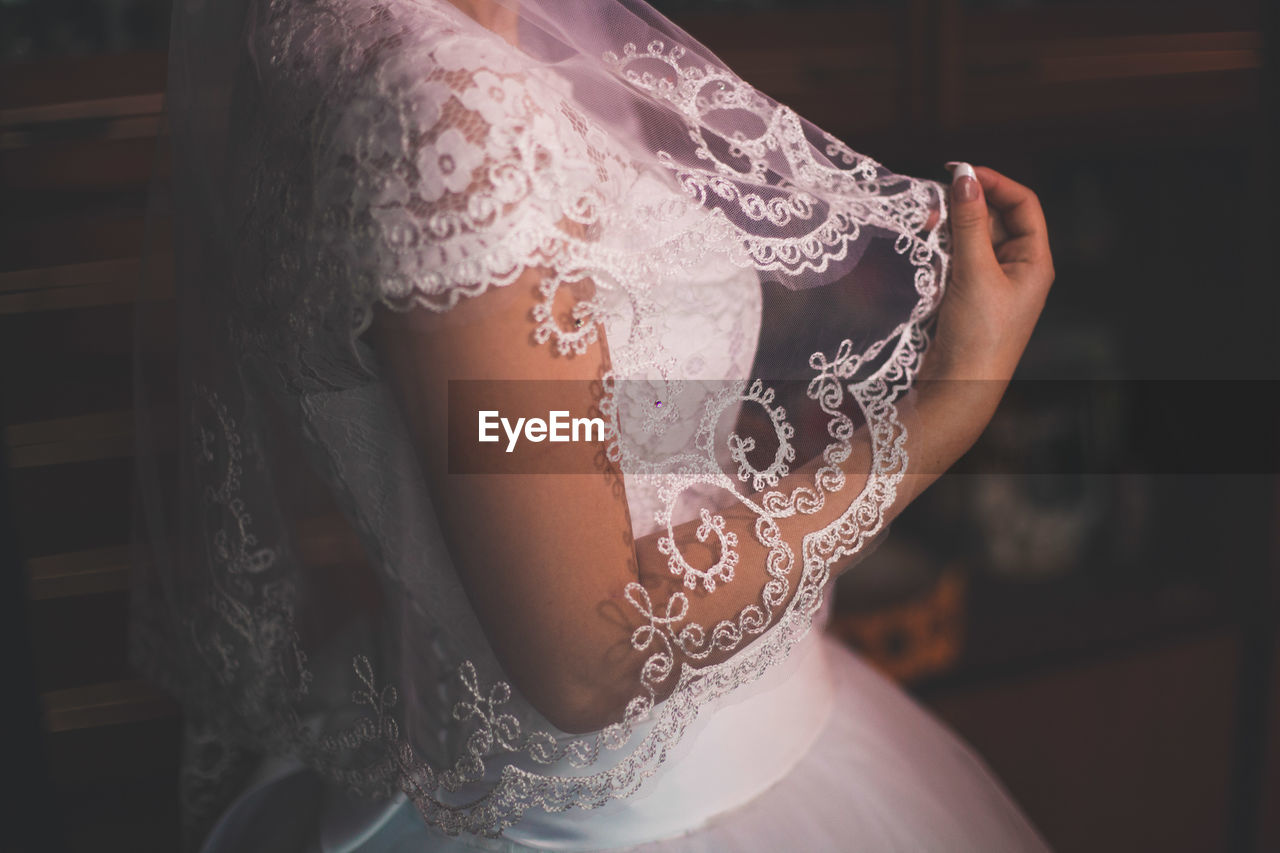 Midsection of bride wearing wedding dress