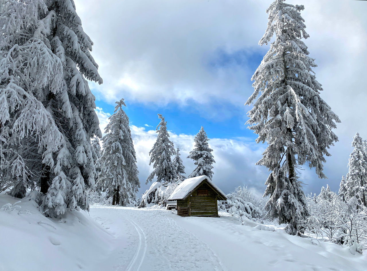 Snow covered shack against sky