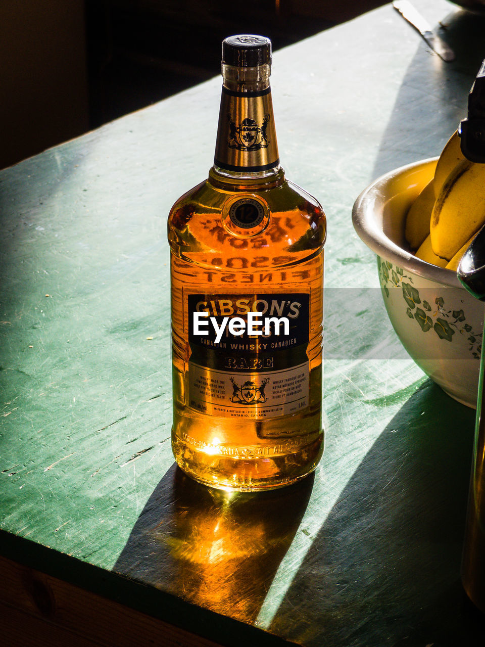 CLOSE-UP OF ILLUMINATED BOTTLE ON TABLE