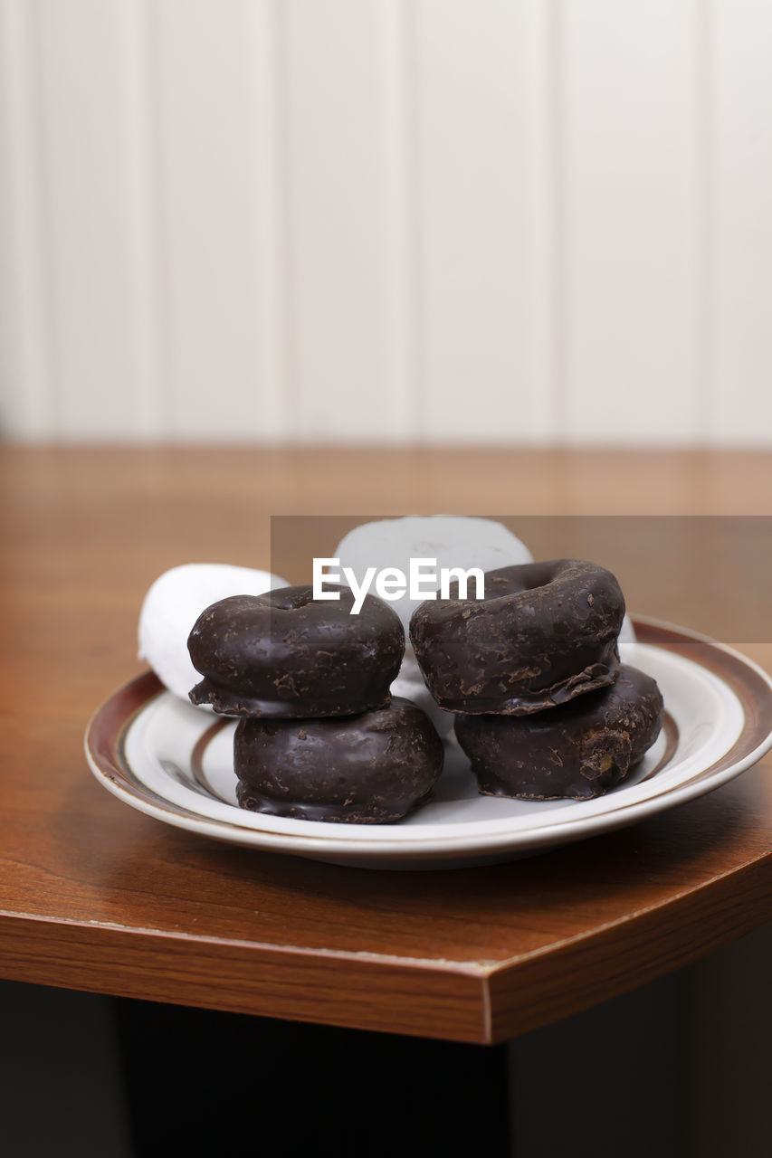 Stack of chocolate donuts in front of a stack of powdered donuts