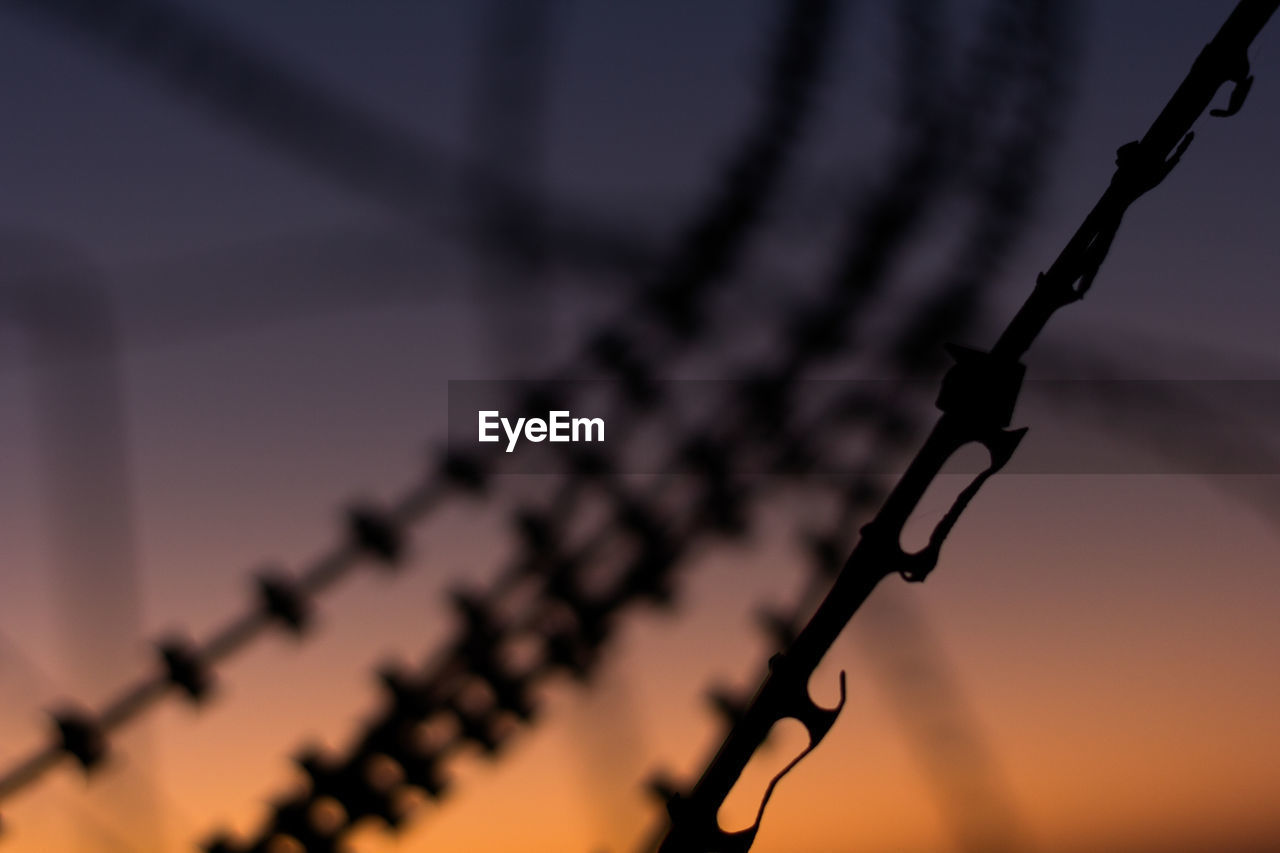 CLOSE-UP OF SILHOUETTE CHAIN HANGING ON METAL FENCE