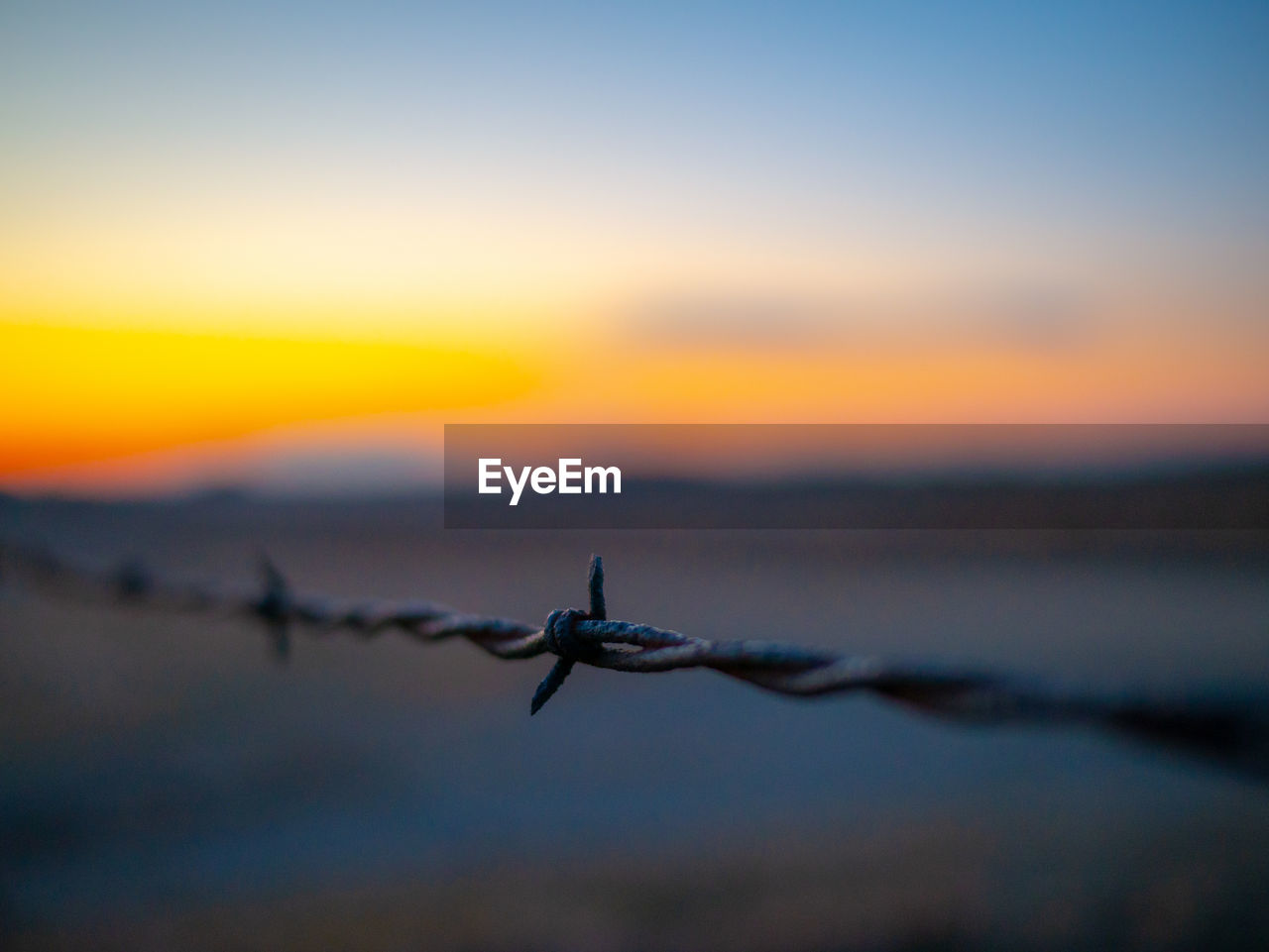 CLOSE-UP OF BARBED WIRE AGAINST SKY