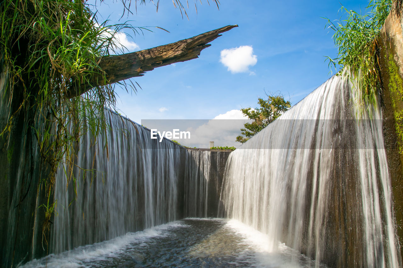 waterfall, water, nature, scenics - nature, tree, environment, plant, body of water, beauty in nature, sky, water feature, motion, tropical climate, travel destinations, travel, environmental conservation, land, cloud, landscape, tourism, flowing water, outdoors, no people, long exposure, sunlight, forest, blue, flowing, vacation, sea, trip, day, non-urban scene, idyllic, social issues, holiday, splashing, summer, architecture