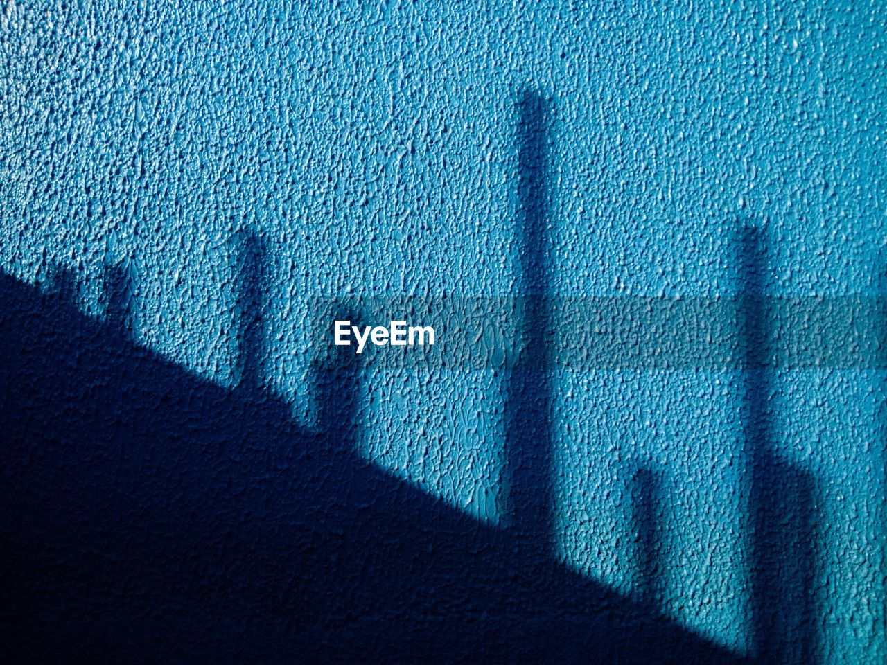 Shadow of construction rods on blue wall