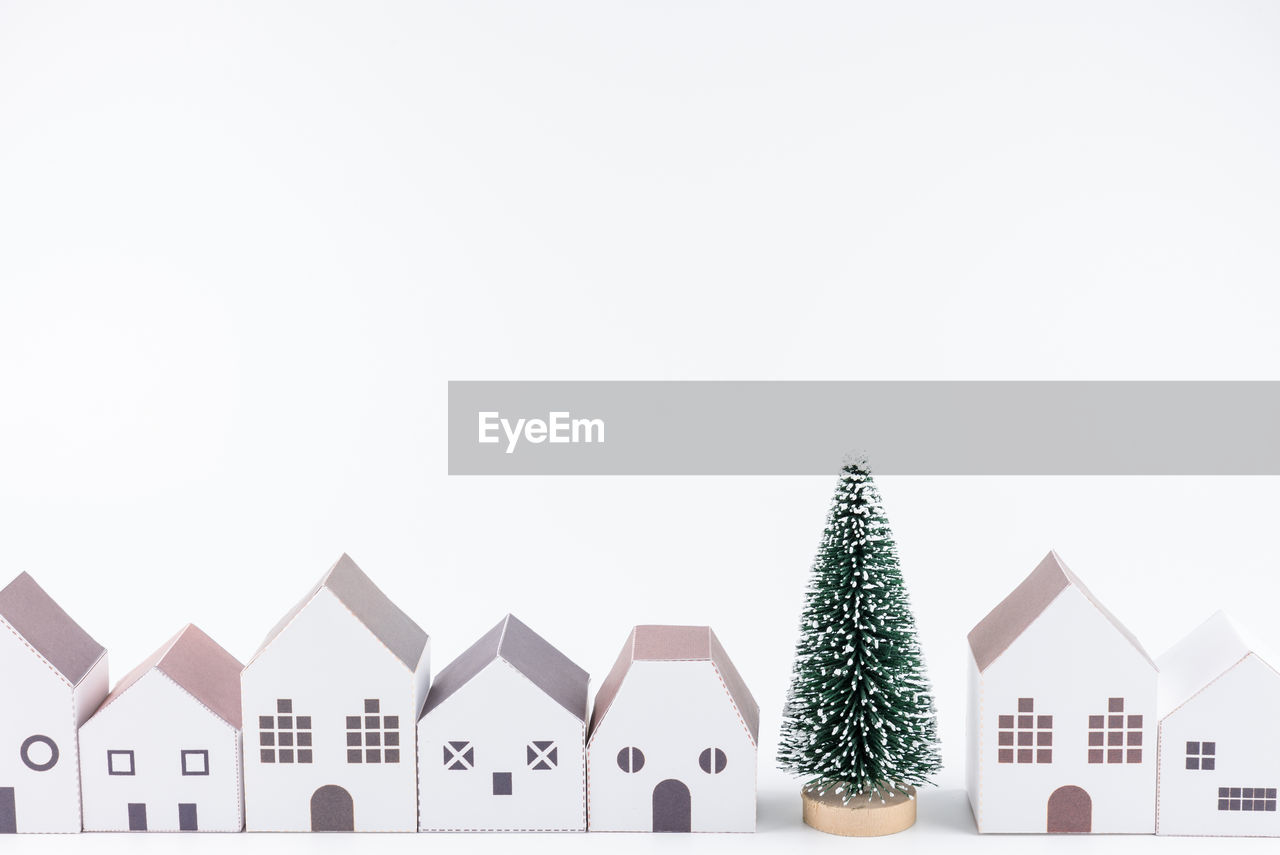 Close-up of christmas tree and model homes against white background