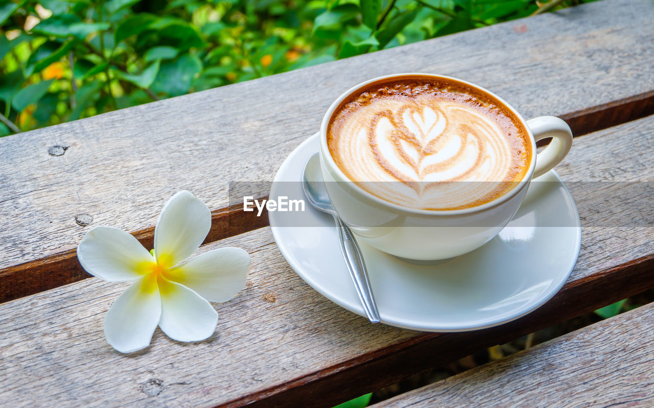 CLOSE-UP OF CAPPUCCINO AND COFFEE CUP ON TABLE