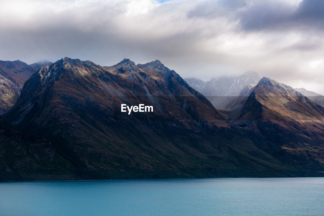 Scenic view of mountains and lake against cloudy sky