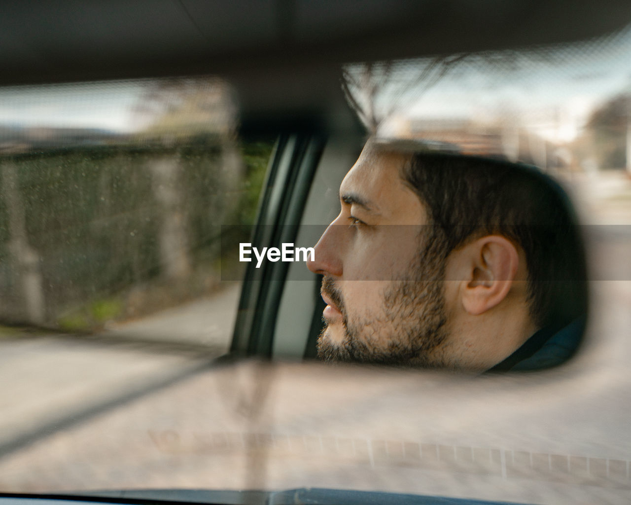 Portrait of young man looking through car window