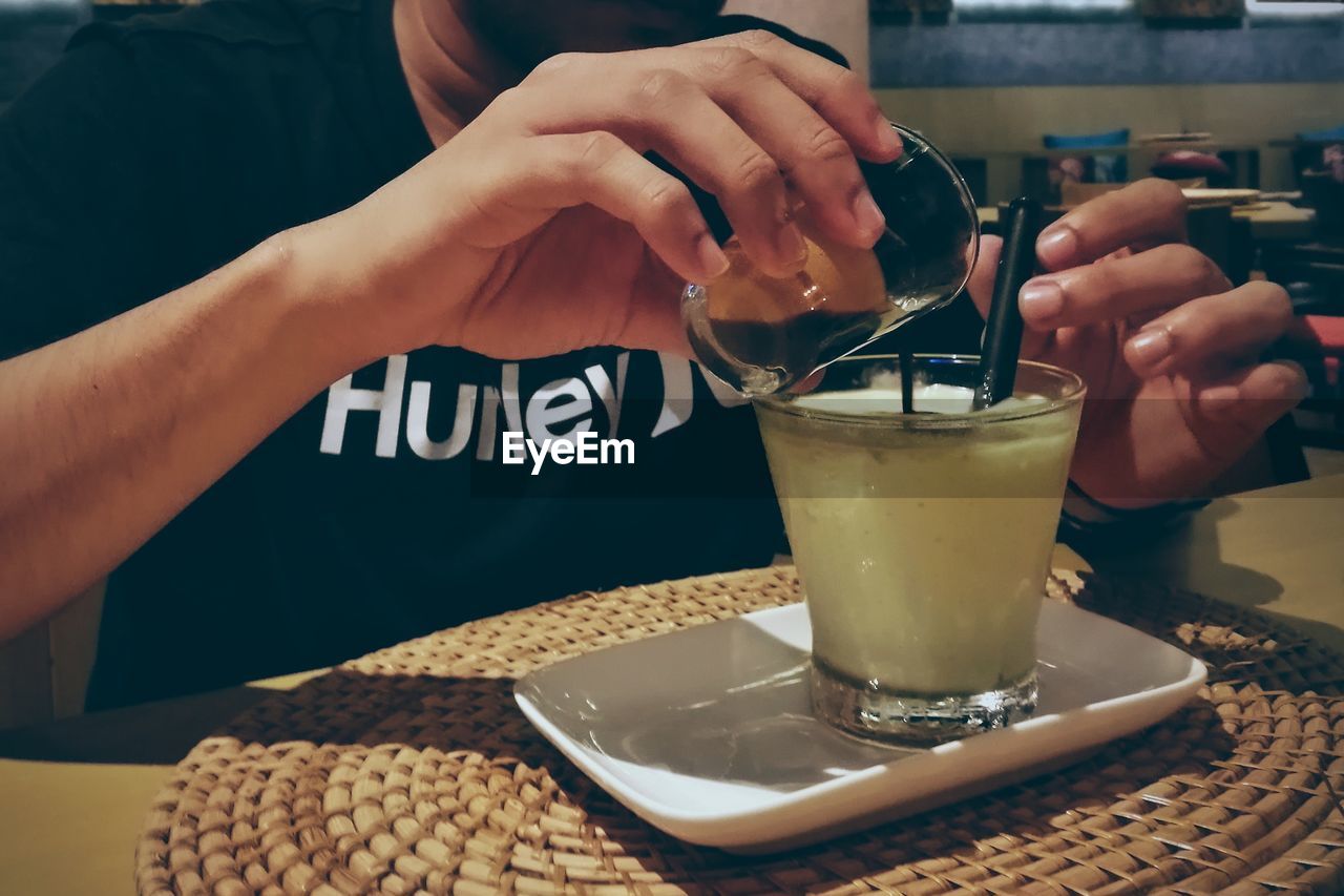 CLOSE-UP OF HAND HOLDING DRINK WITH JUICE