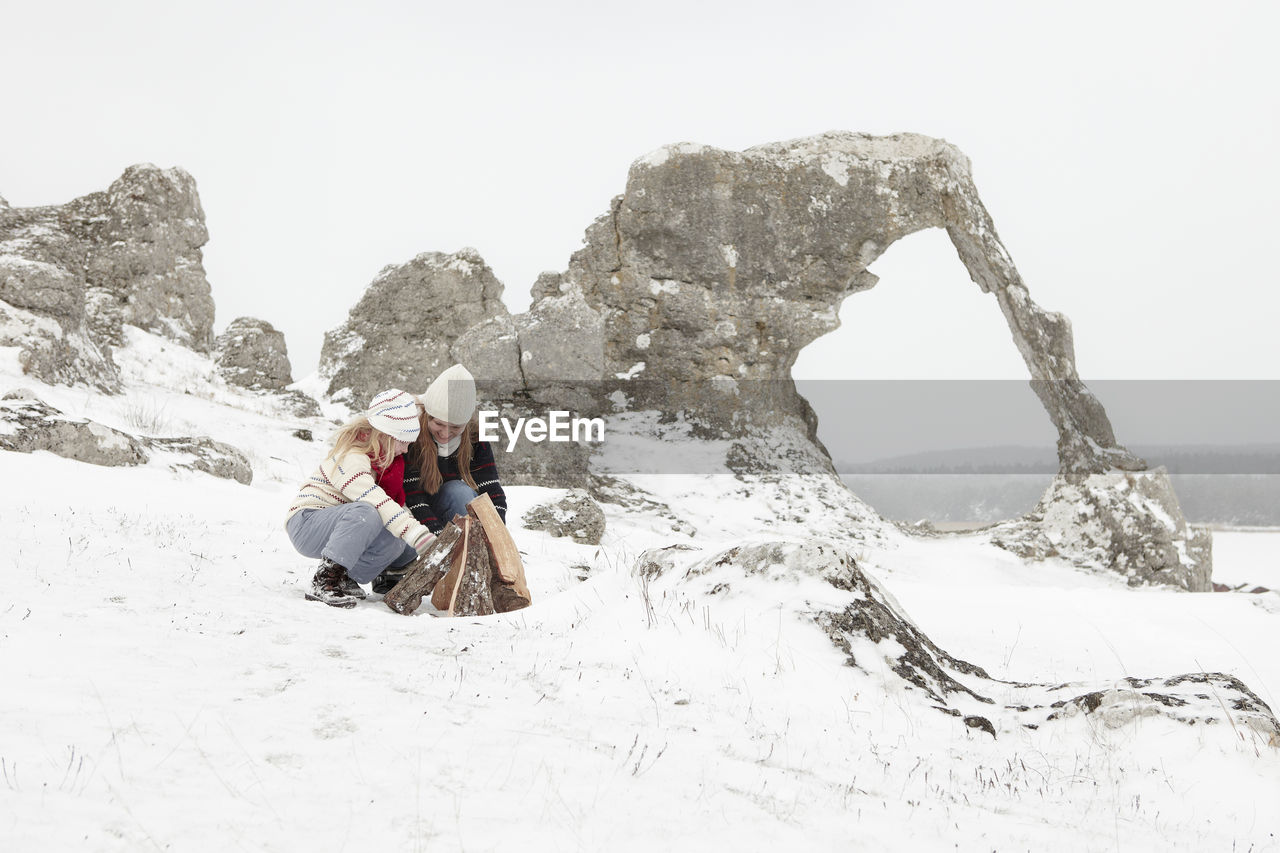 Mother with daughter making campfire at winter