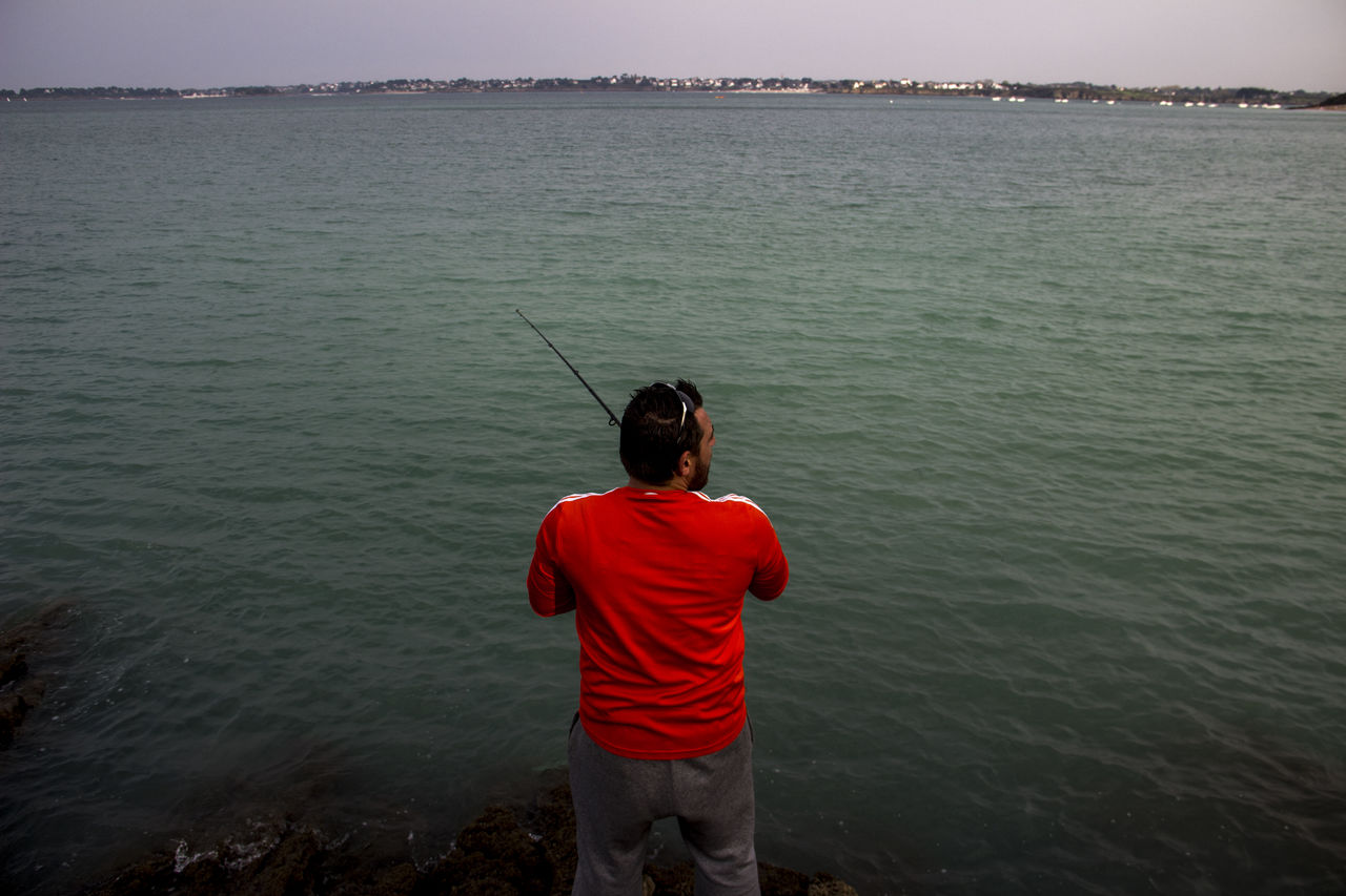 water, rear view, one person, sea, fishing, men, nature, sky, beauty in nature, standing, rod, casting, scenics - nature, activity, leisure activity, fishing rod, angling, lifestyles, holiday, adult, fisherman, land, outdoors, vacation, tranquility, trip, beach, three quarter length, environment, tranquil scene, recreation, relaxation, red, non-urban scene, full length, child, occupation, childhood