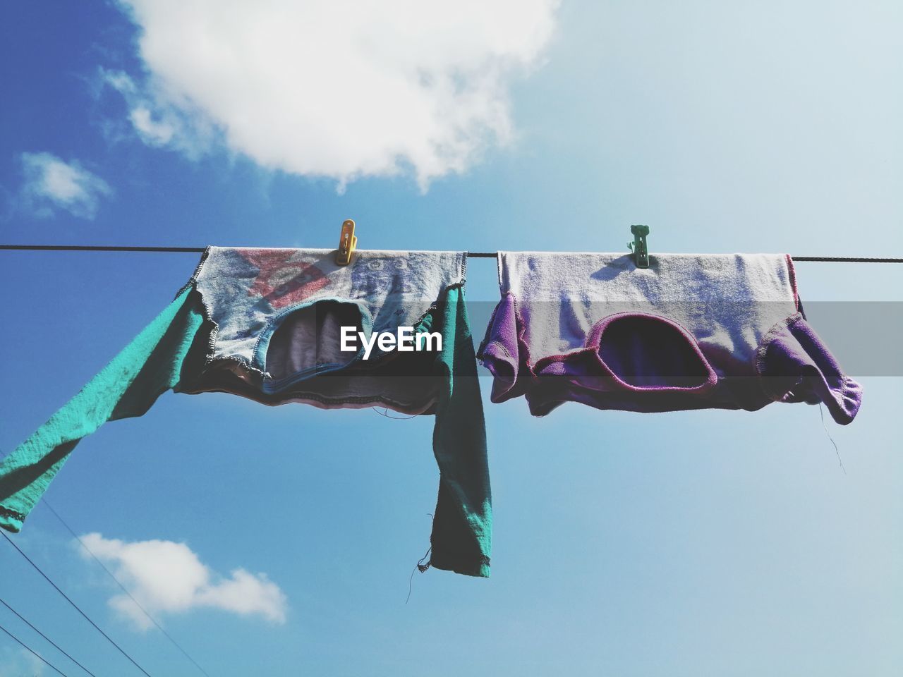 LOW ANGLE VIEW OF FLAGS HANGING ON CLOTHESLINE AGAINST SKY