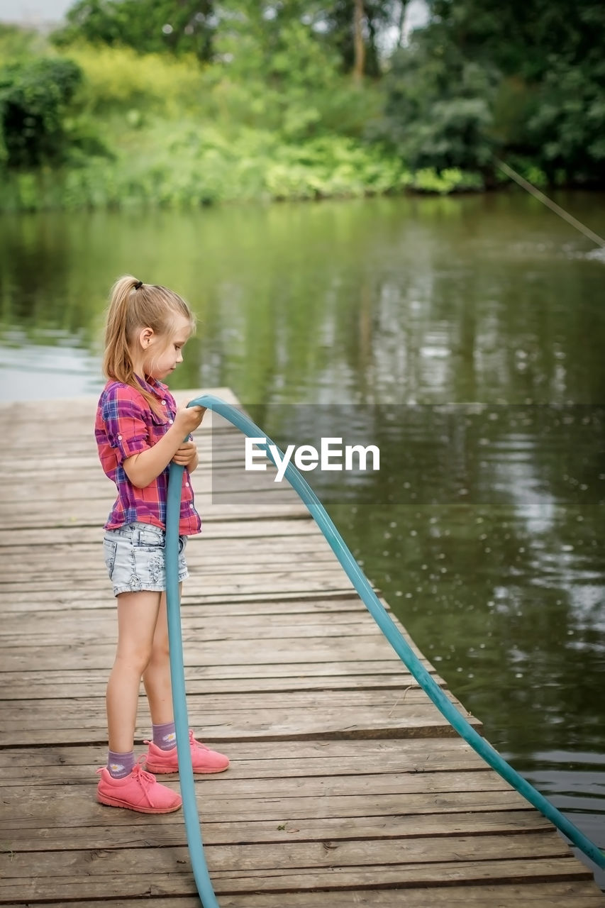 full length of cute girl playing with fishing rod