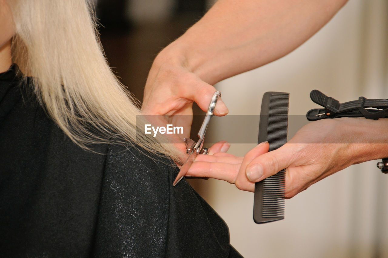 Cropped hands of hairdresser cutting woman hair