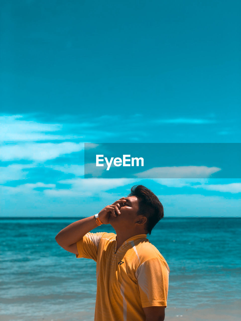 BOY STANDING ON BEACH AGAINST SKY