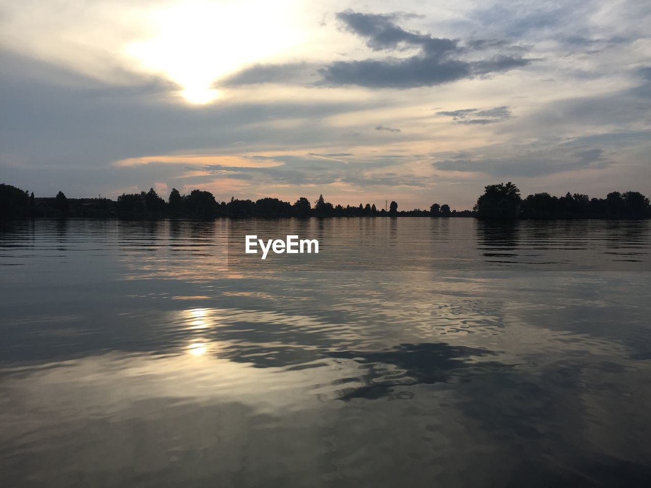 Scenic view of lake against cloudy sky during sunset