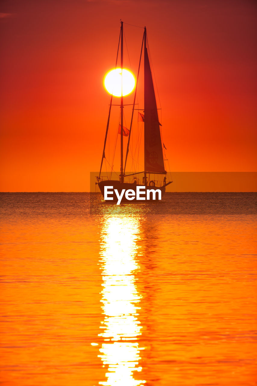 Silhouette of sailboat on sea against sky during sunset