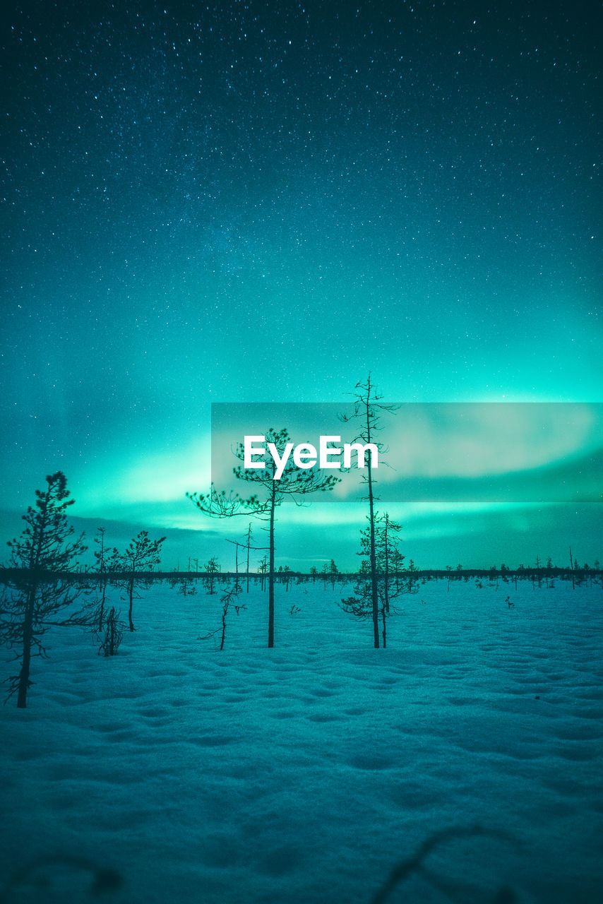Scenic view of snow covered land against sky during aurora borealis
