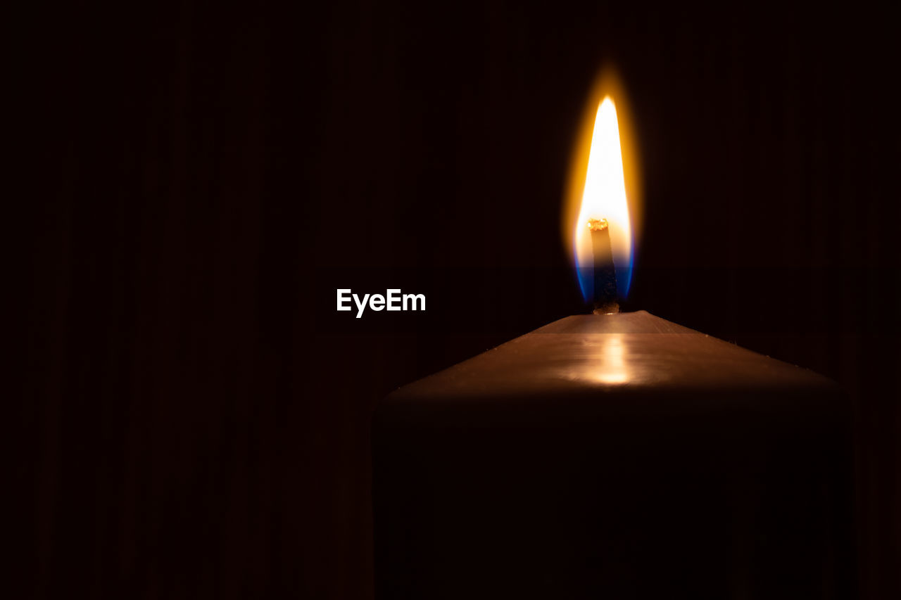 CLOSE-UP OF LIT CANDLES IN DARKROOM