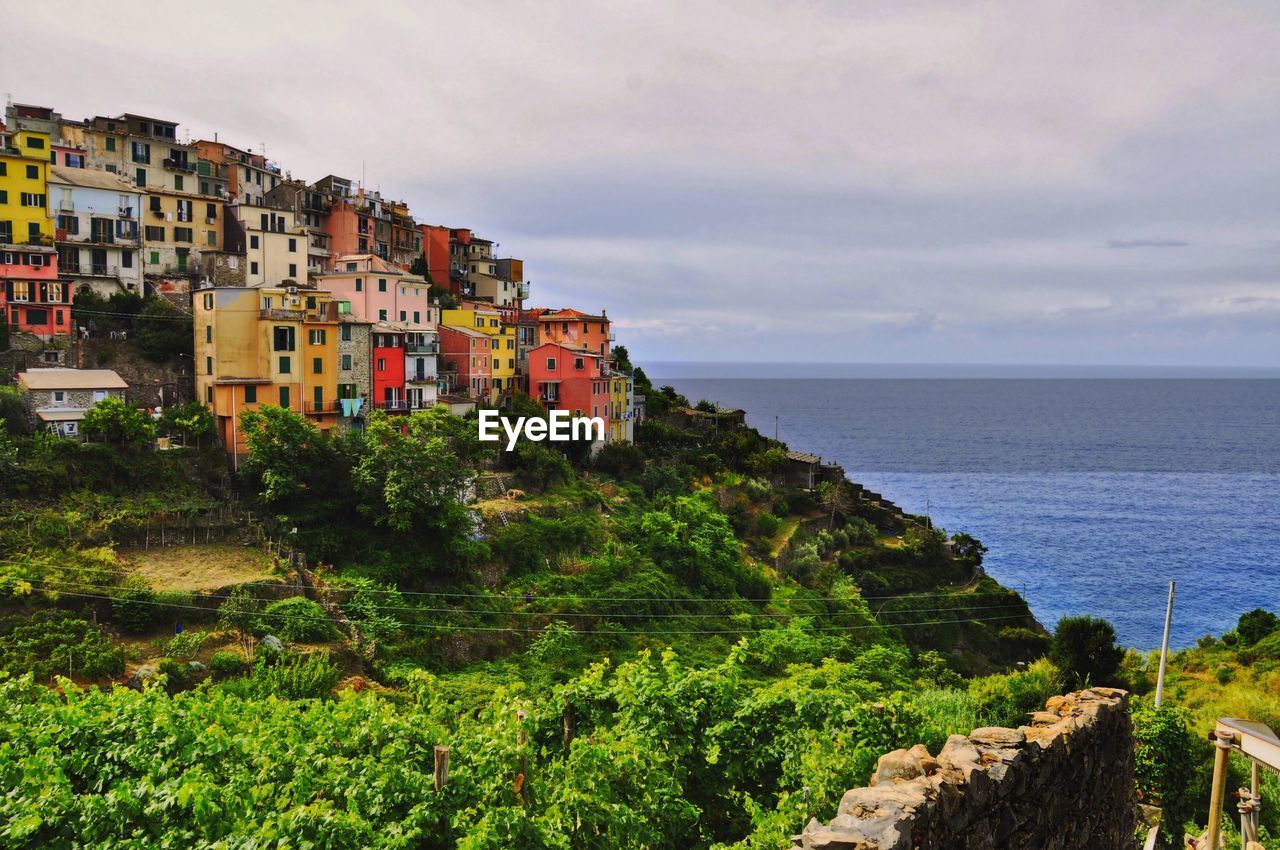 Houses by sea against sky in town