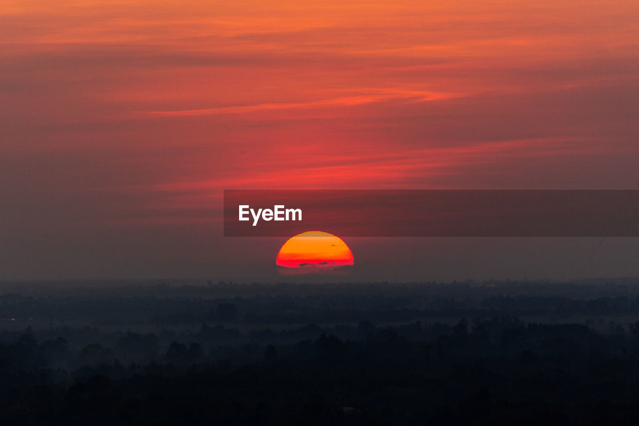 Silhouette landscape against orange sky