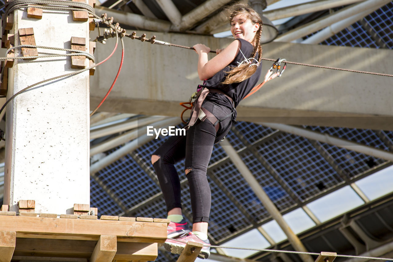 Low angle view of teenage girl walking on rope