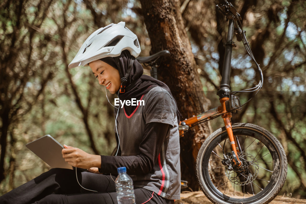 Smiling woman using digital tablet at park