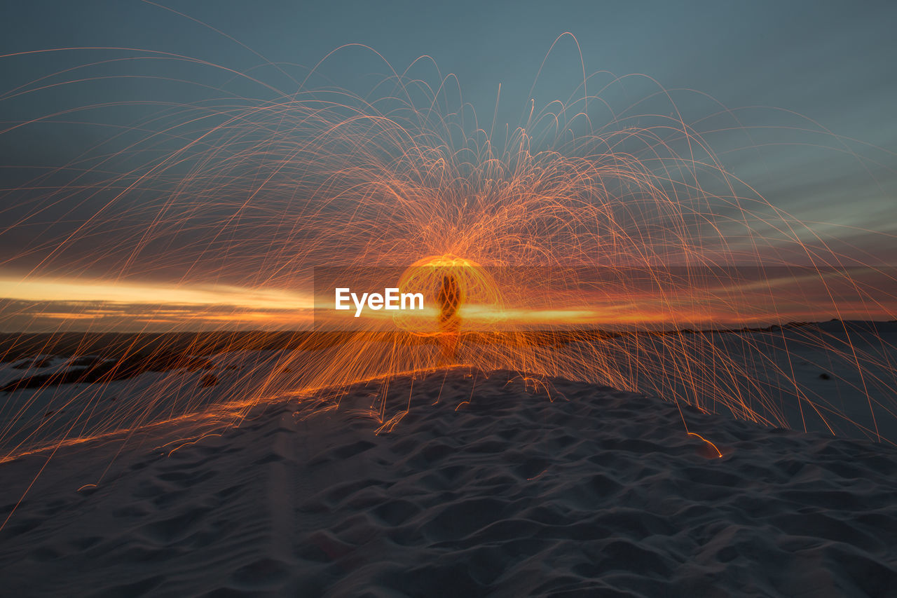 Light trails on beach against sky at night