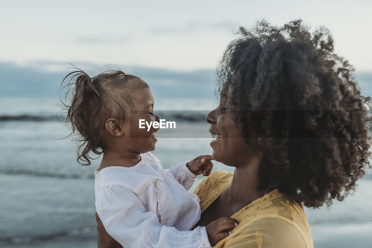 Side view of mother and daughter embracing in the ocean