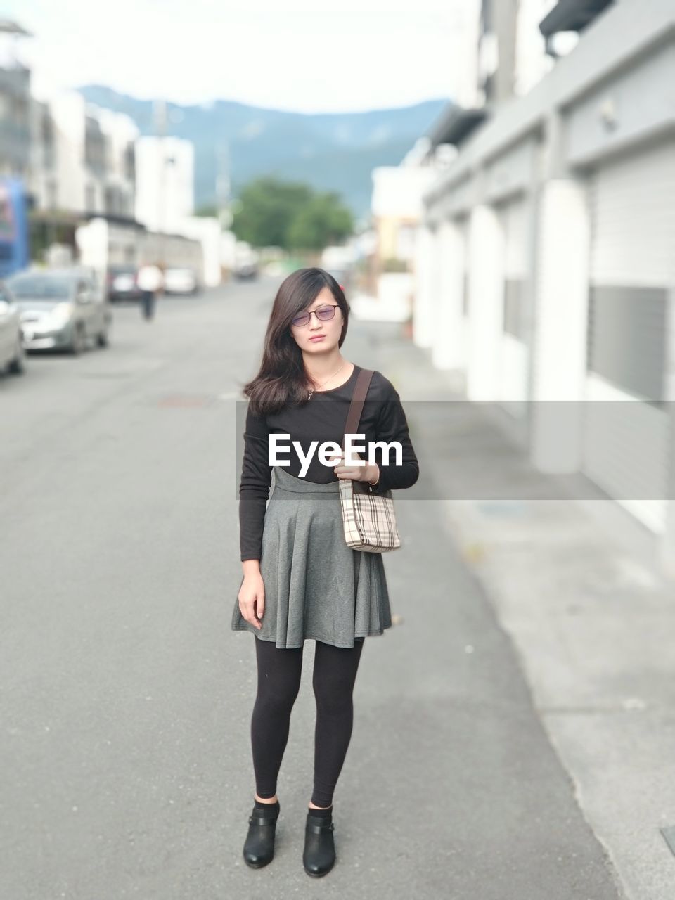 Portrait of young woman standing on road