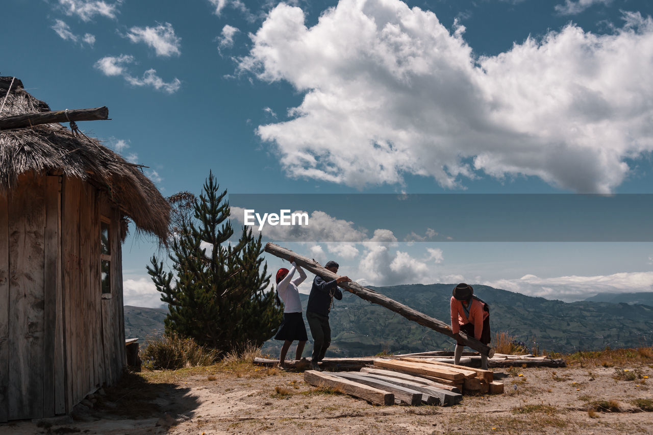 PEOPLE STANDING ON WOOD AGAINST SKY