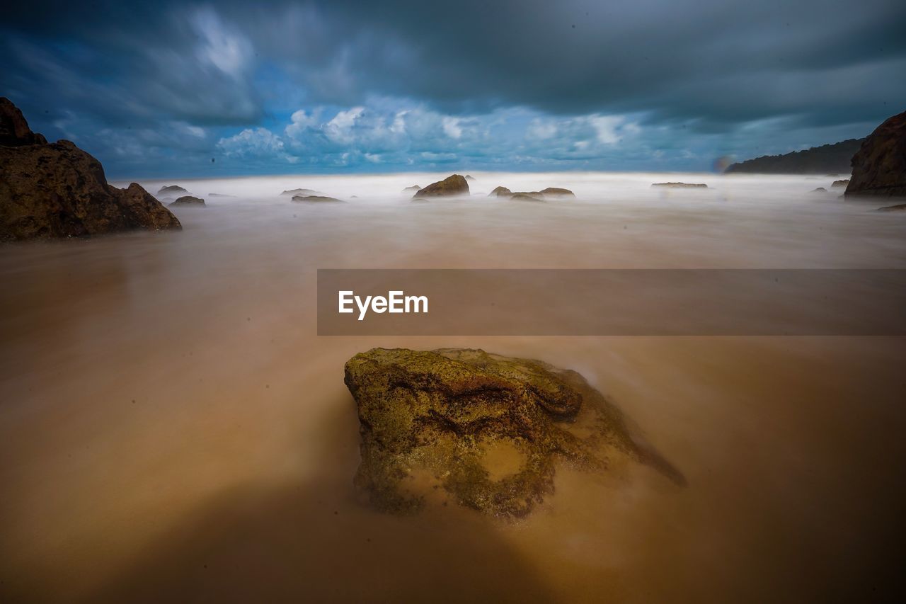 Scenic view of rocks on beach against sky