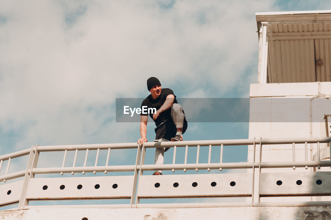 Men standing on railing against sky