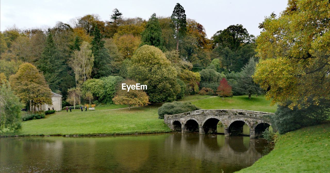 Arch bridge over lake against trees during autumn