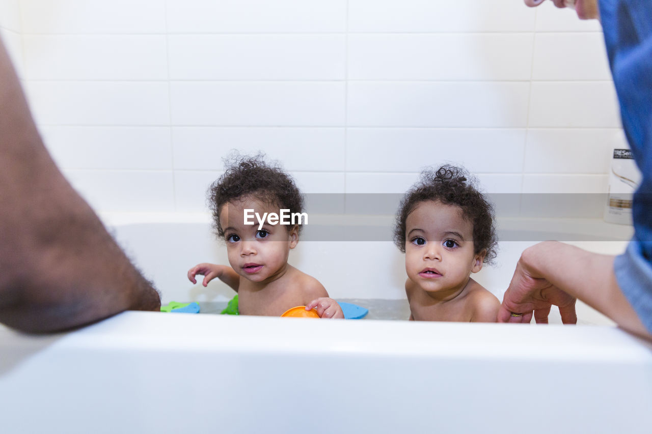 Cropped image of parents bathing daughters together in bathtub