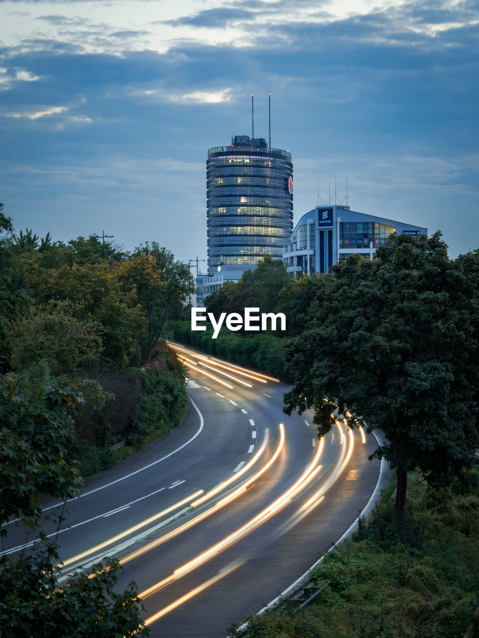 ROAD AMIDST TREES AND CITY AGAINST SKY