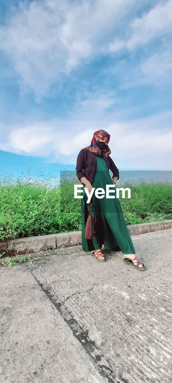 SIDE VIEW OF WOMAN SITTING ON LAND