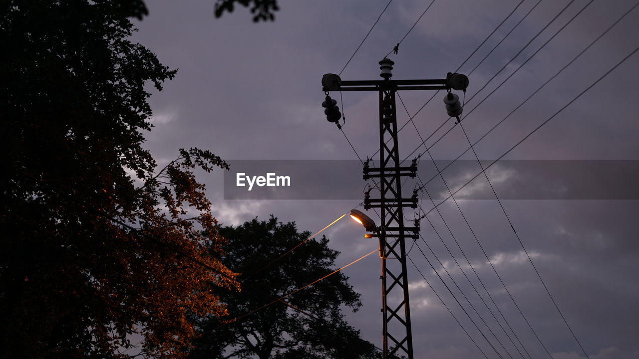 LOW ANGLE VIEW OF ELECTRICITY PYLON AGAINST SKY AT SUNSET