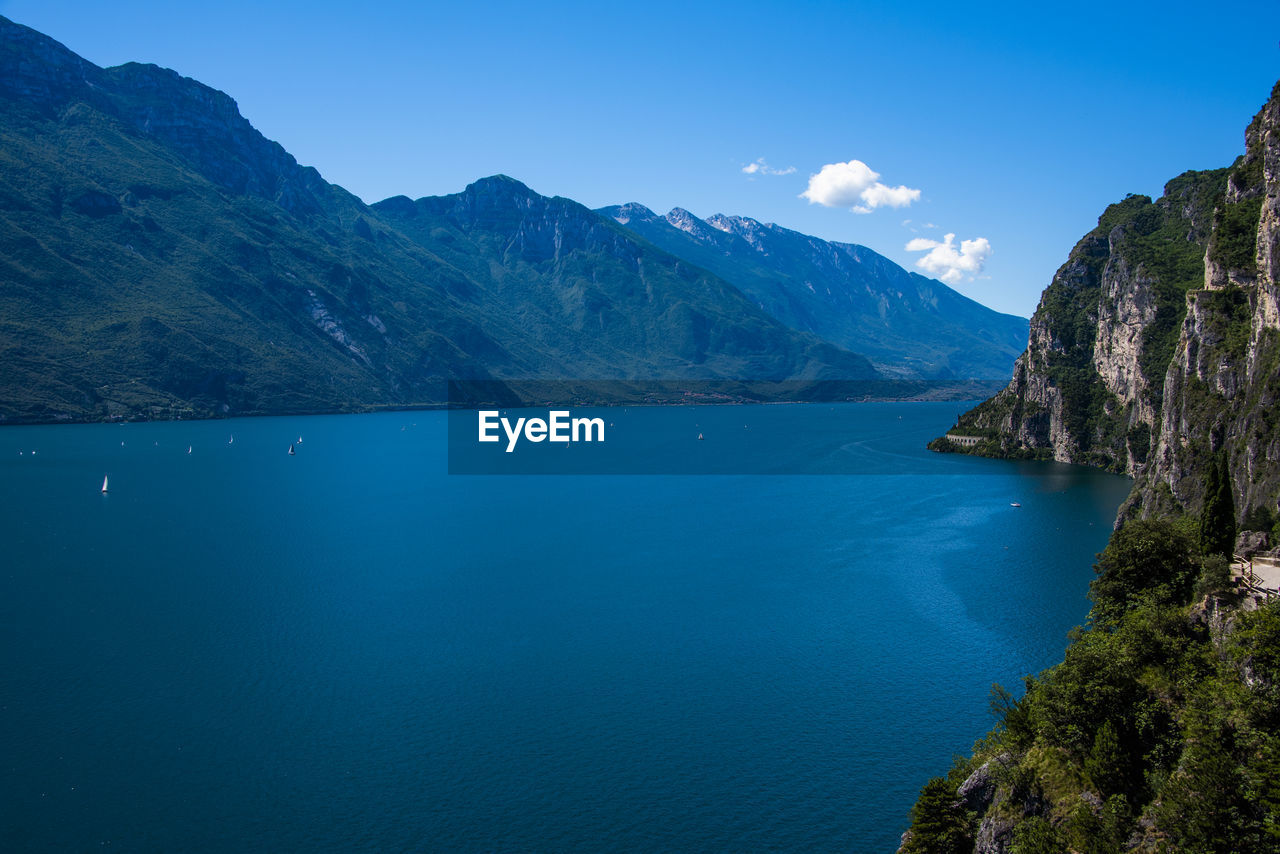 Scenic view of sea and mountains against blue sky