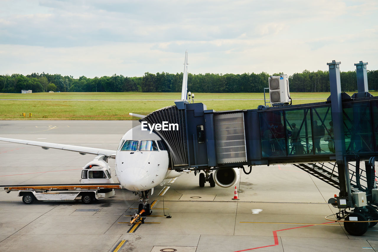 transportation, air vehicle, airplane, airport, mode of transportation, travel, airport runway, aircraft, aviation, jet bridge, infrastructure, vehicle, air force, airliner, sky, tarmac, aerospace industry, passenger boarding bridge, cloud, nature, loading, journey, transport, airport departure area, boarding, road, no people, business, day, outdoors, gate, jet aircraft