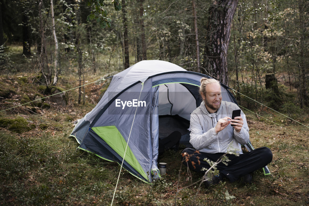 Man using phone in front of tent